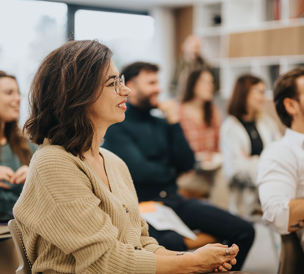 Smiling woman participating in a professional workshop with colleagues in a modern office setting
